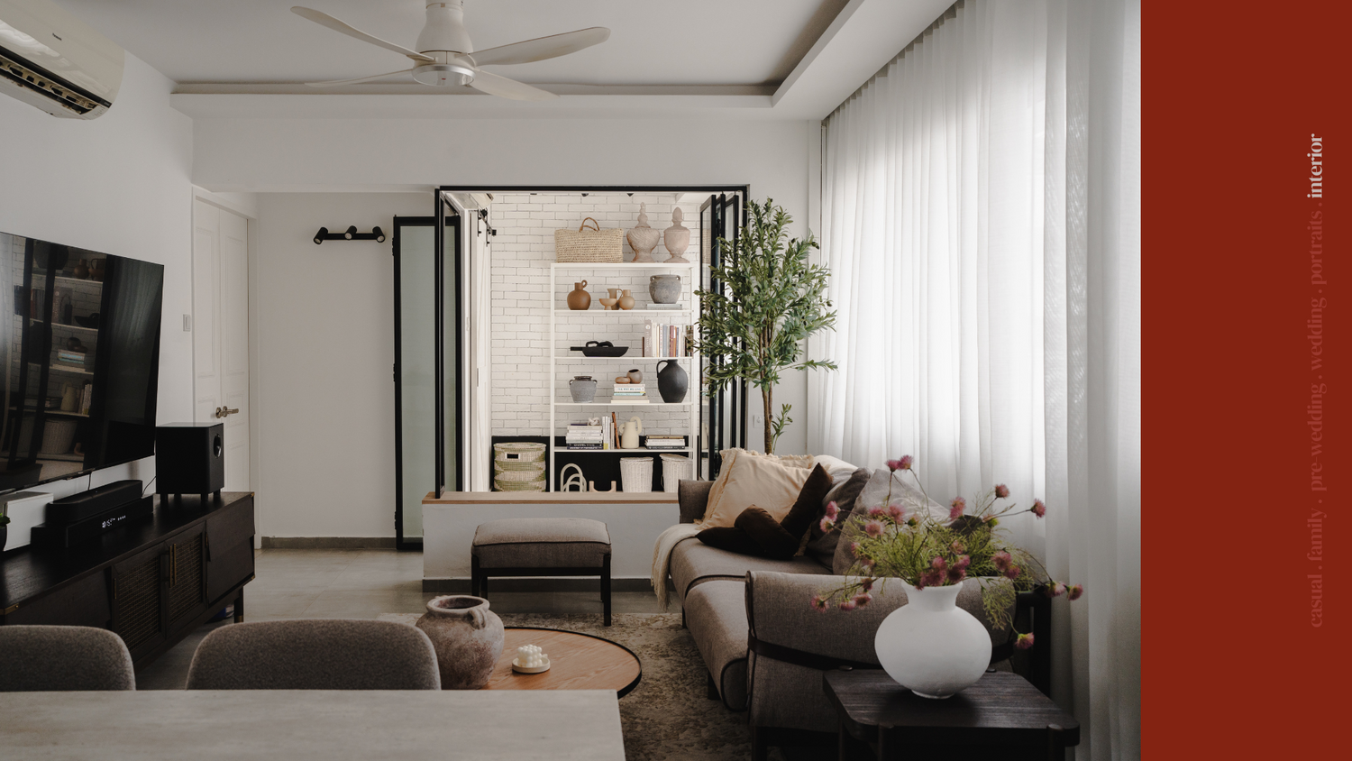 Modern living room interior with white walls, grey sofa, and minimalist shelving display.