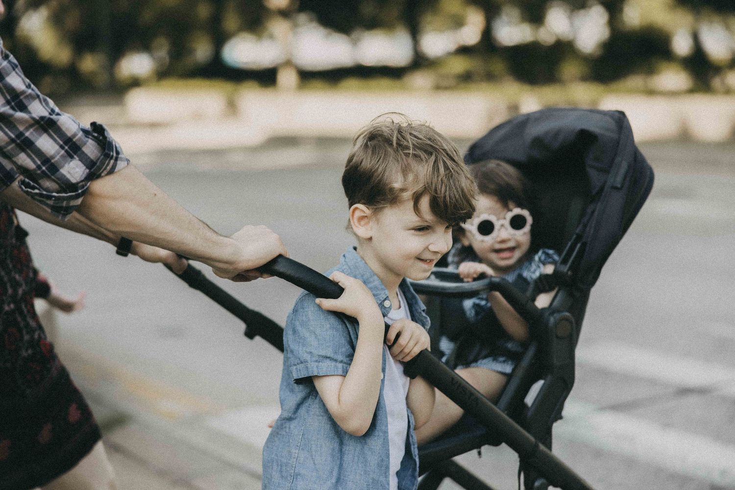 Young child and stuffed toy monkey with sunglasses in stroller during outdoor walk.