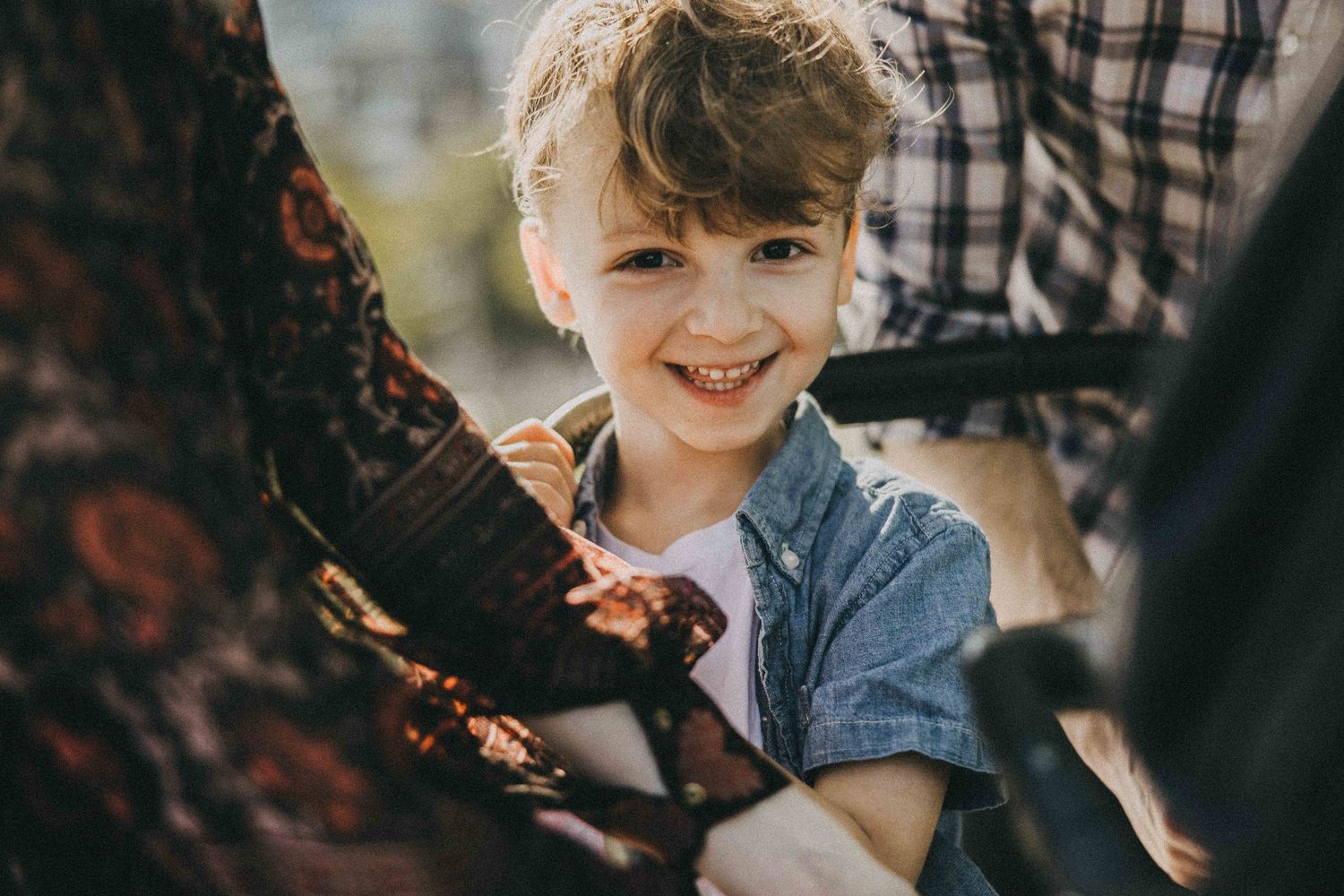 Happy child laughing and playing with adult outdoors in warm sunlight.
