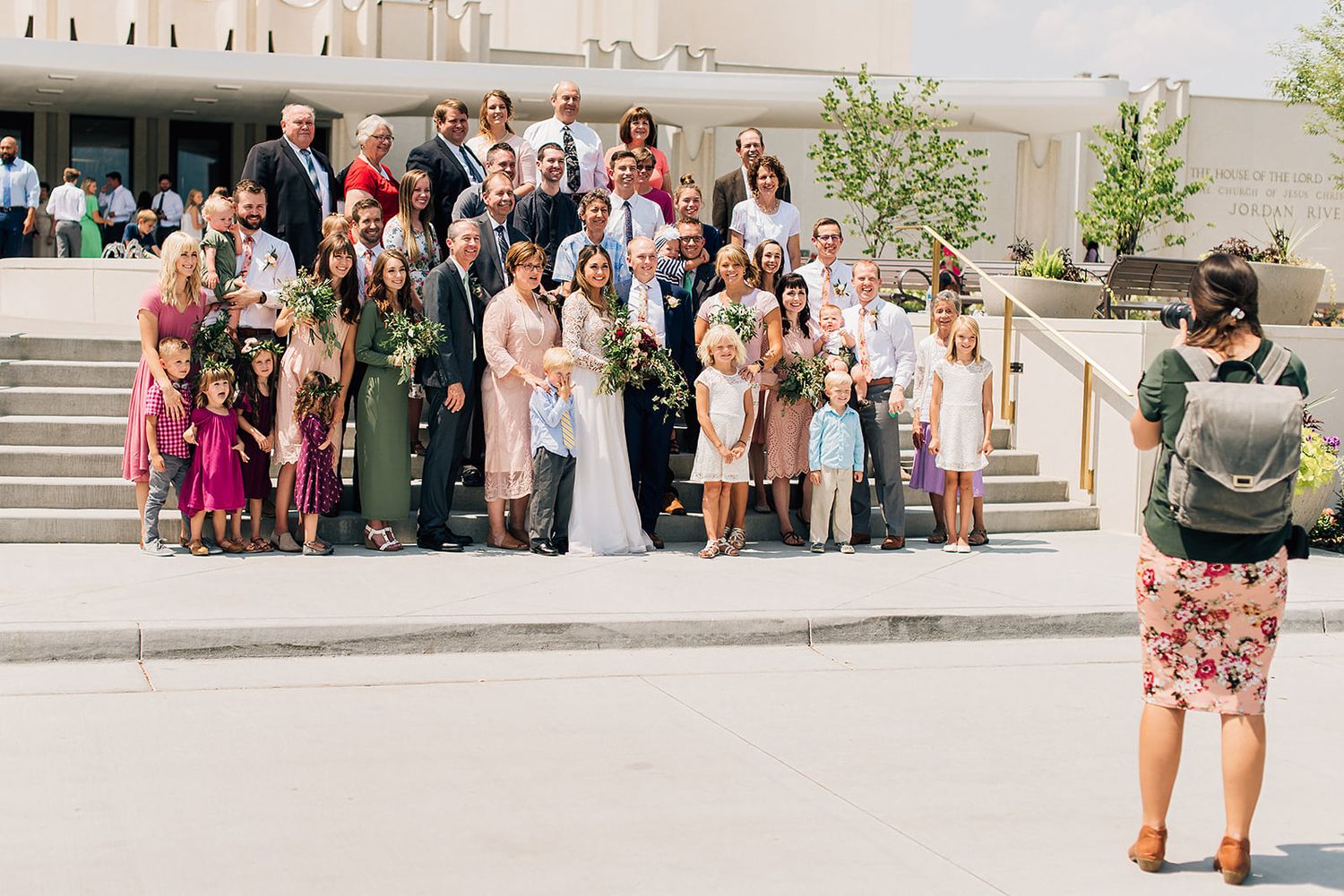 Large wedding party gathering on outdoor steps for formal group photo.