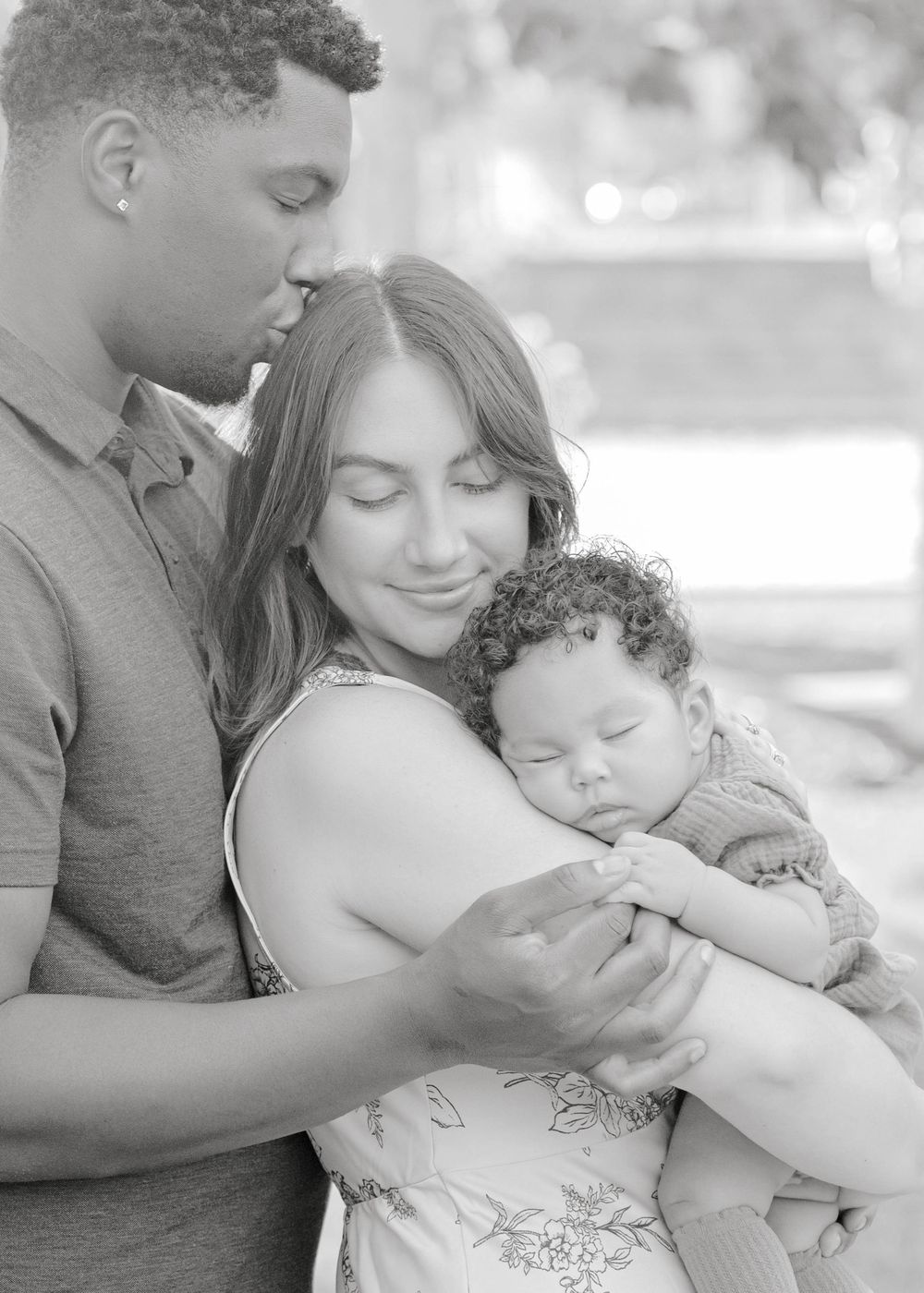A tender black and white photo series showing intimate family moments between parents and their sleeping baby.