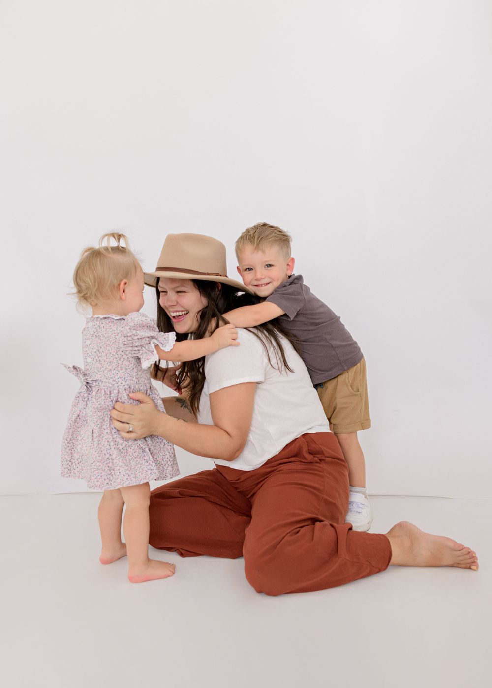 Family portrait showing tender moment between parent and children against white background.