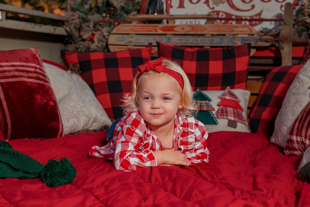 A cozy holiday scene with buffalo plaid decor, red pillows and festive Christmas decorations in the background.