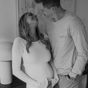 A joyful black and white maternity photo capturing a candid laughing moment between a couple.