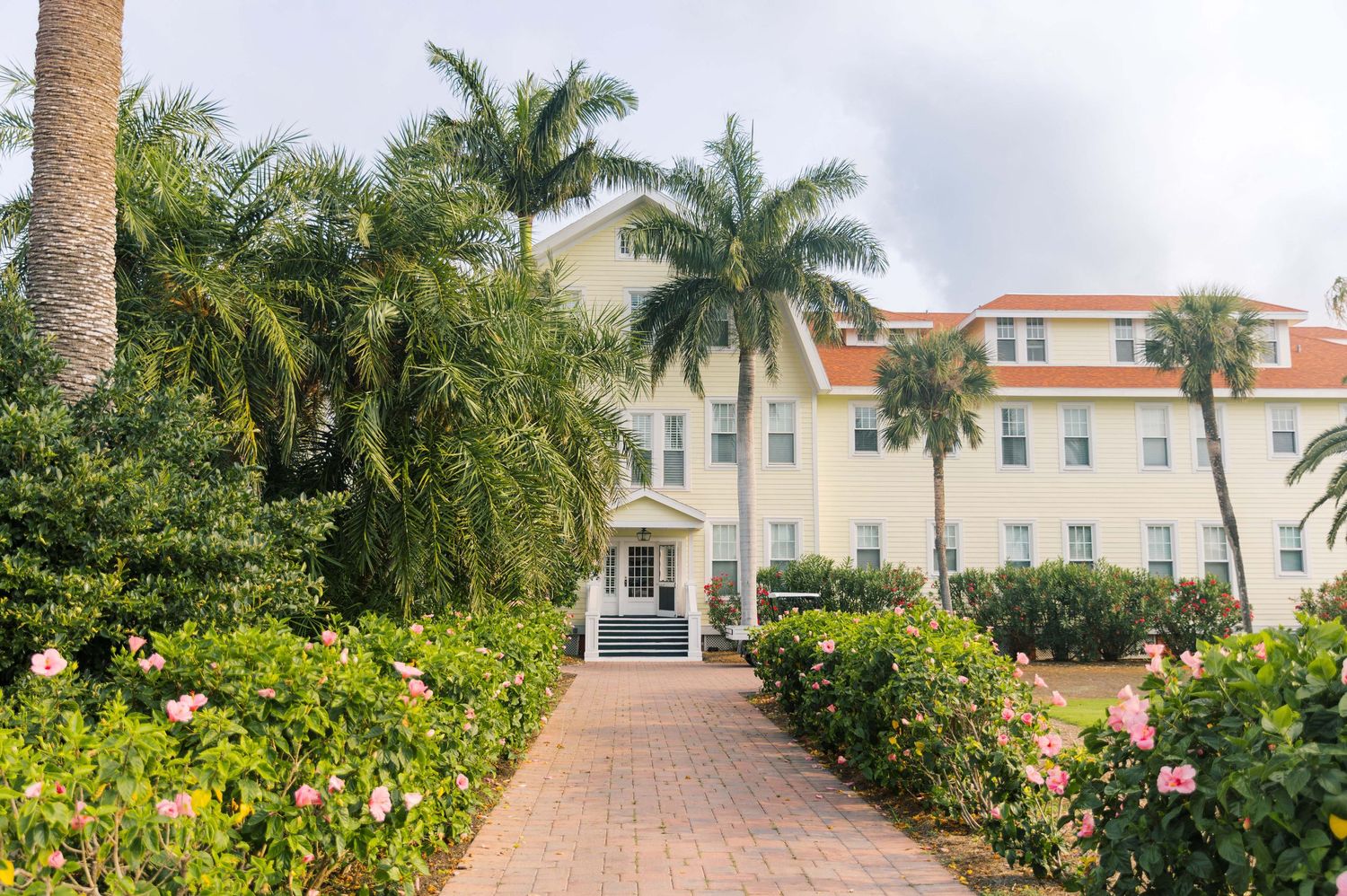 Mediterranean style building with palm trees and landscaped garden path entrance.