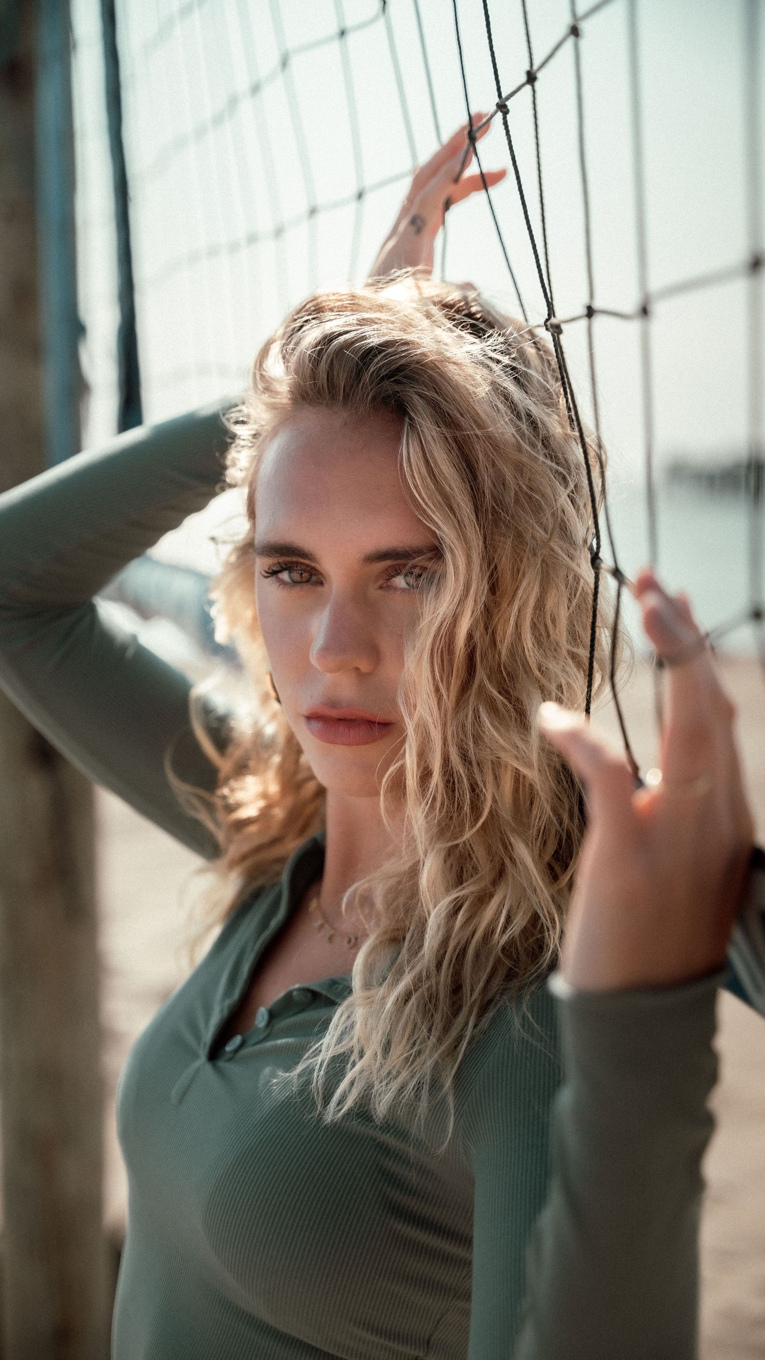 Artistic portrait with dramatic lighting against wire mesh background.