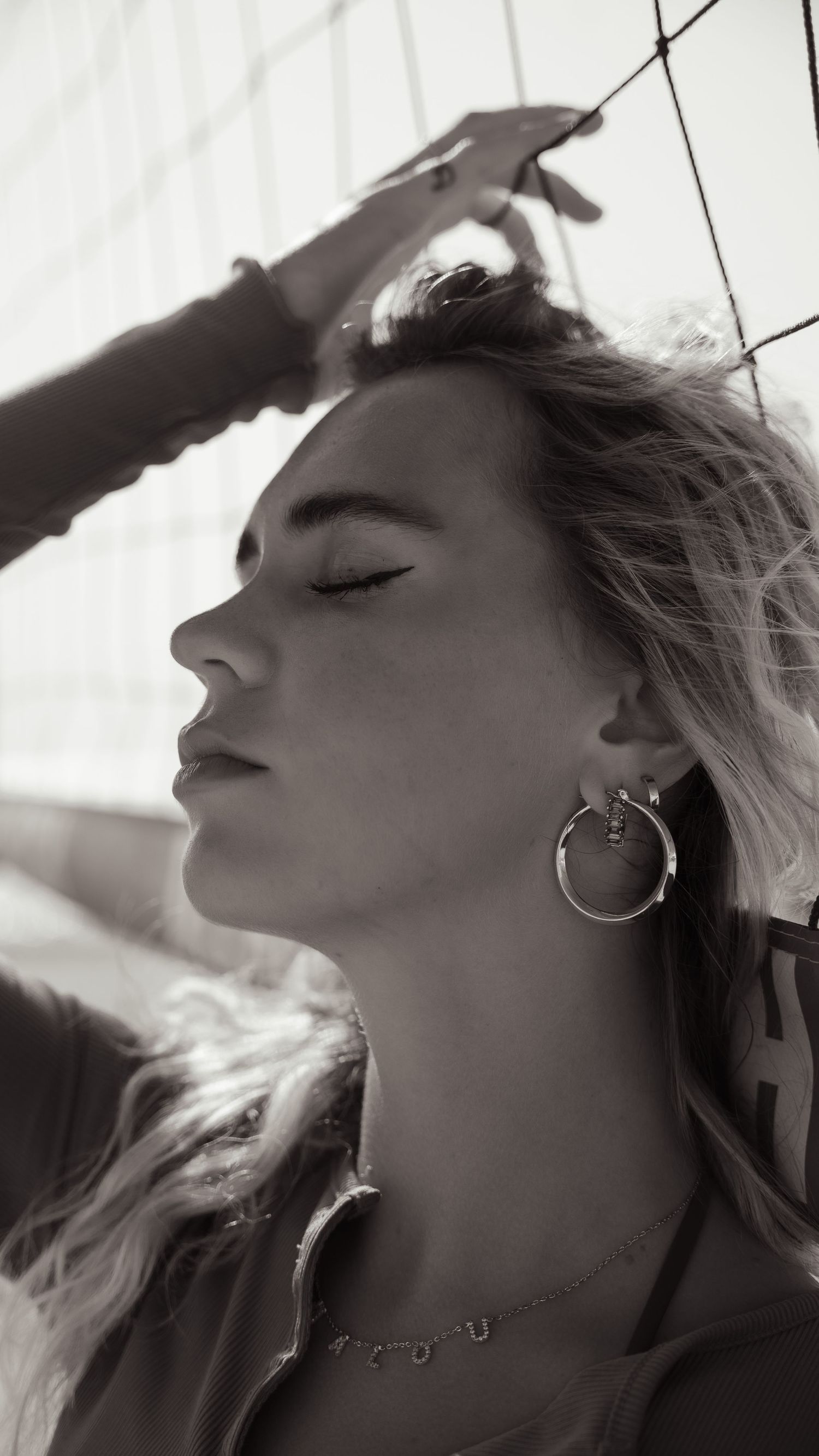 Black and white profile portrait with hoop earring and wind-swept hair.