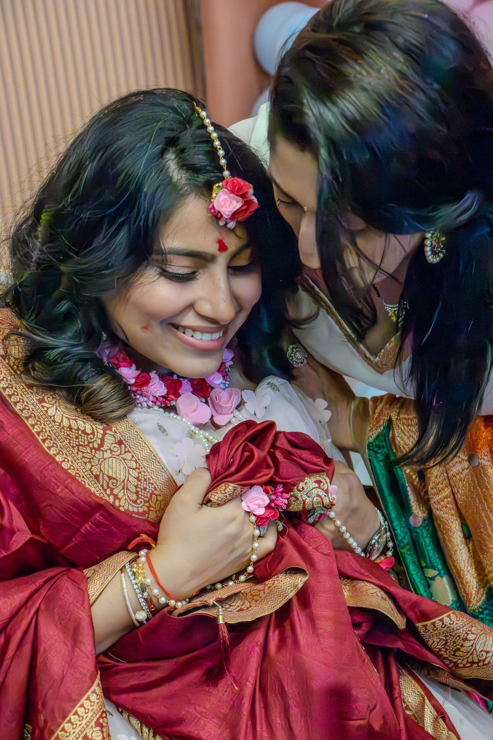 Traditional celebration with women in red and gold sarees adorned with flowers.
