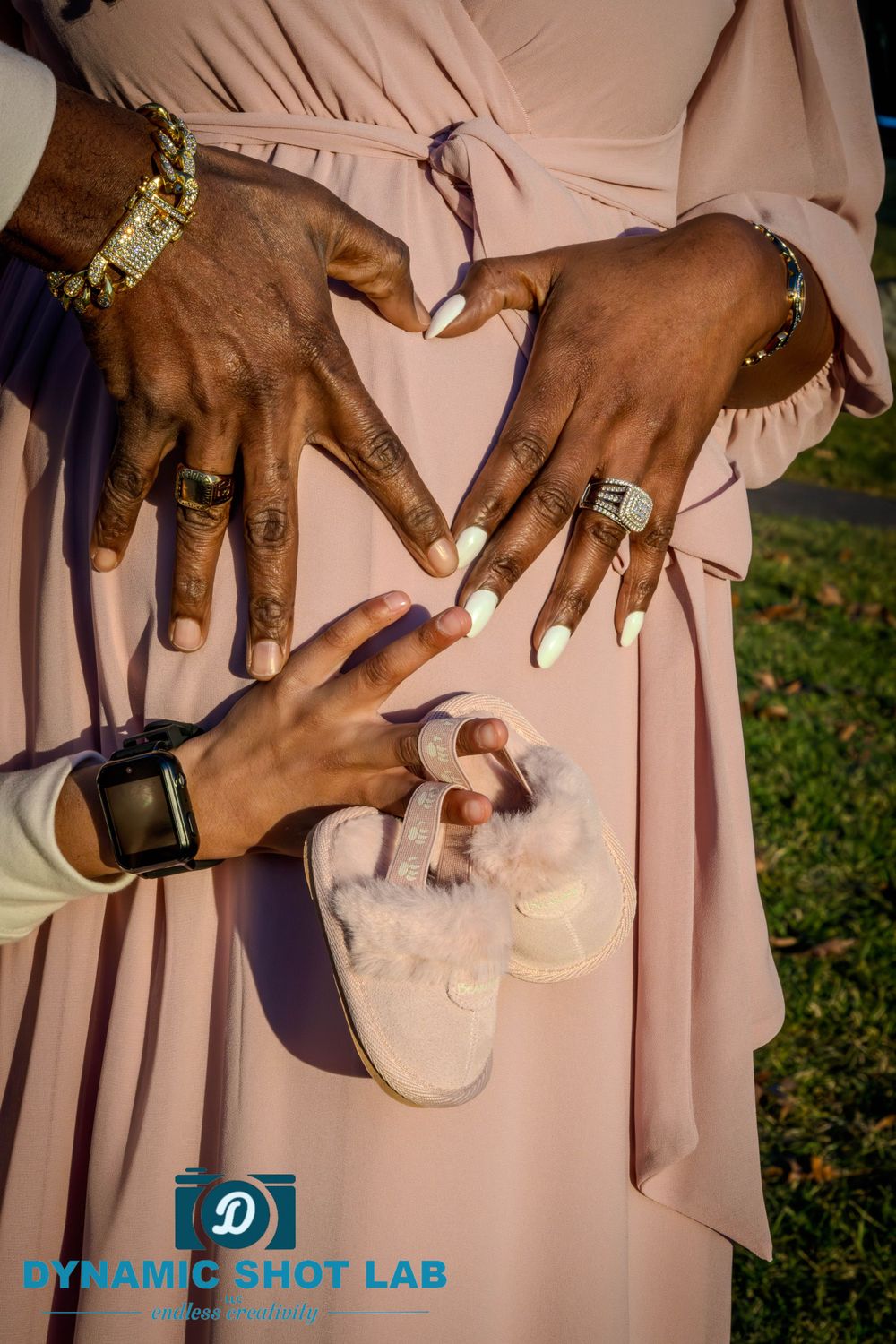 Close-up of hands showing rings and holding tiny baby shoes.