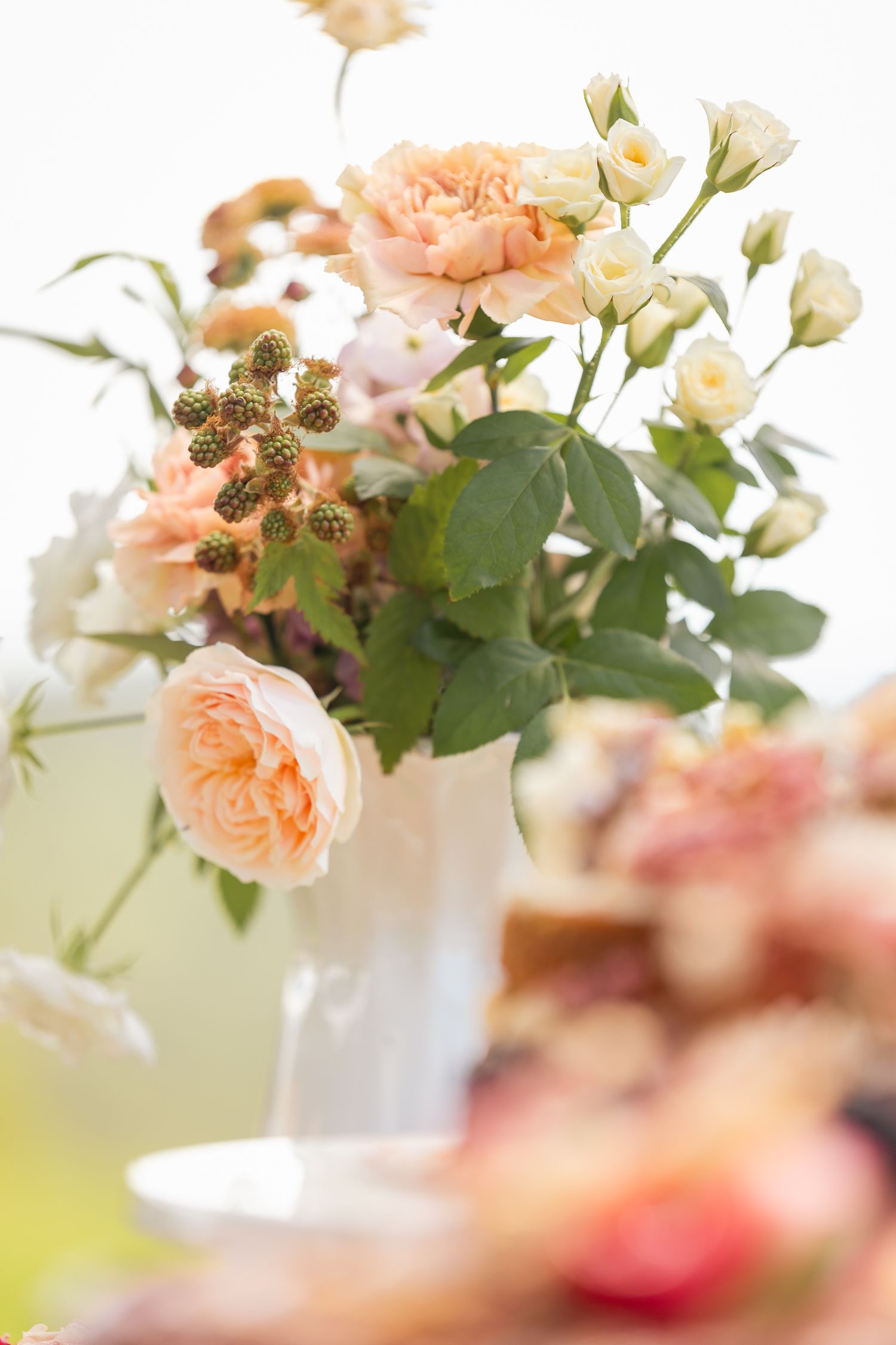 Delicate peach and cream floral arrangement with roses and greenery in soft focus. Maleny Wedding Venue Sunshine Coast.