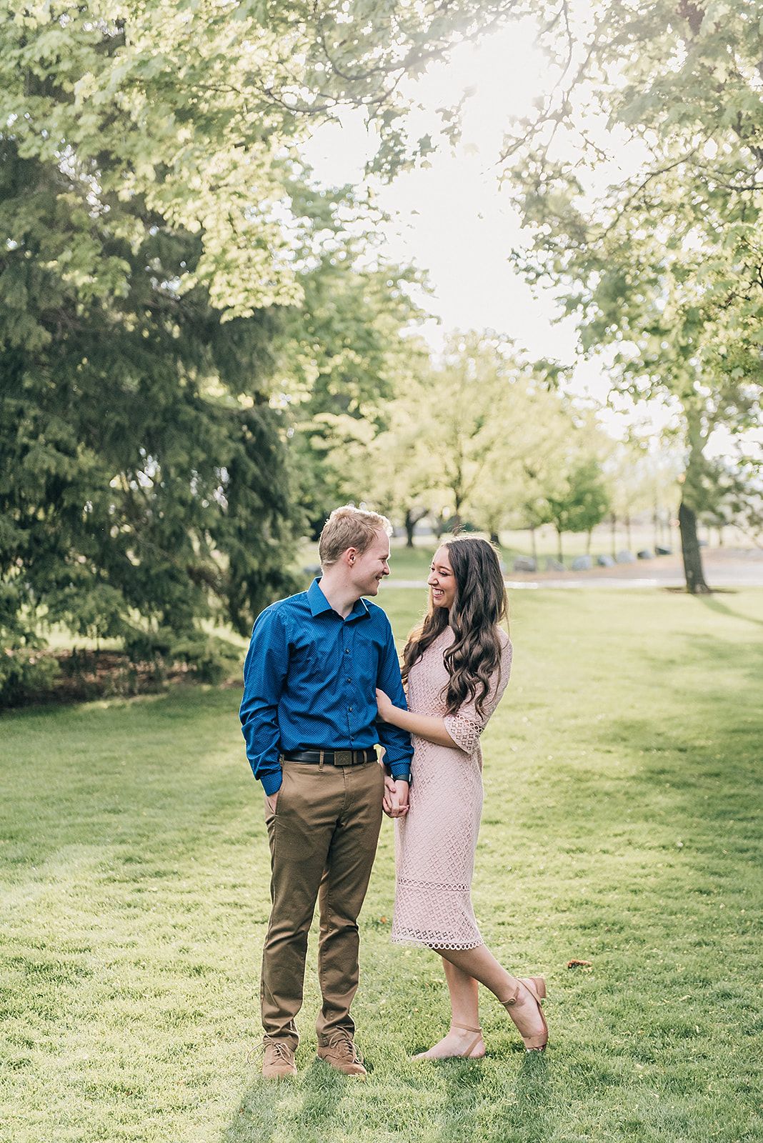 A couple shares a joyful moment together on a sunny day in a park setting.
