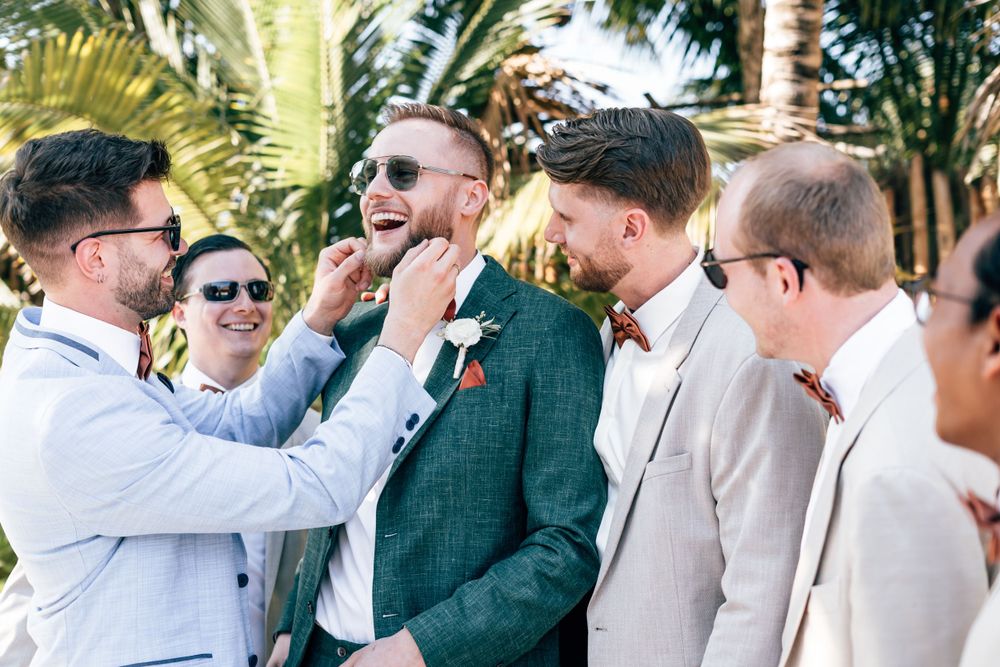 Wedding party celebrating outdoors in light colored suits against tropical greenery, Blue Venado, Mango Weddings.