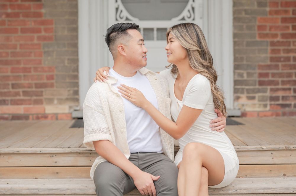 Couple in coordinated outfits sharing romantic moment on architectural front steps.