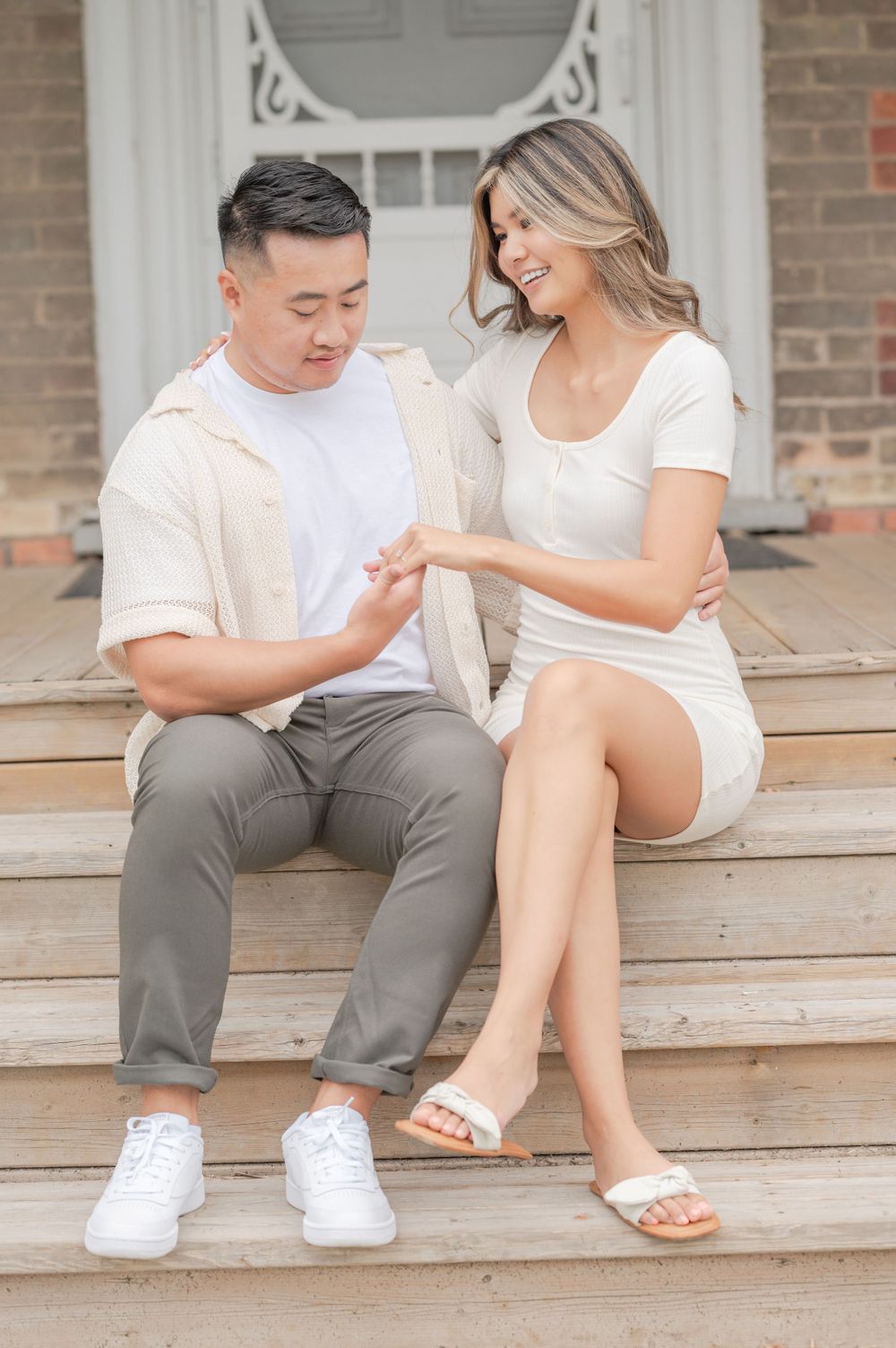 Joyful couple sharing playful moment while sitting on historic building's front steps.