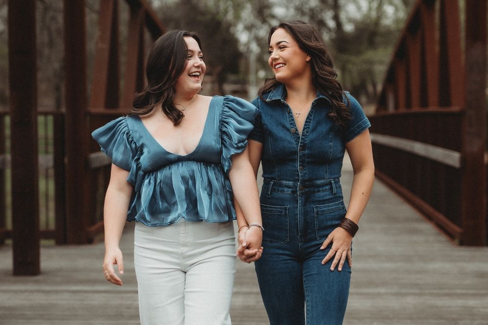Two friends walking together on rustic bridge in coordinated outfits.
