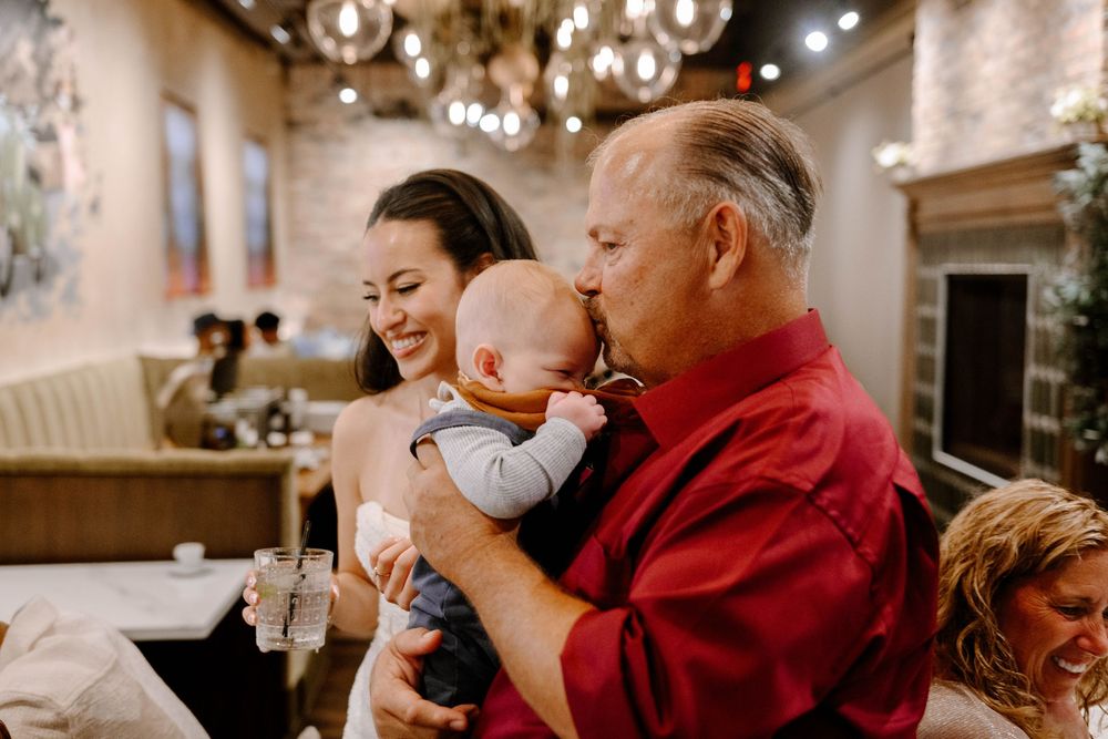People gathered in a restaurant with hanging lights enjoy an intimate family celebration and meal together.
