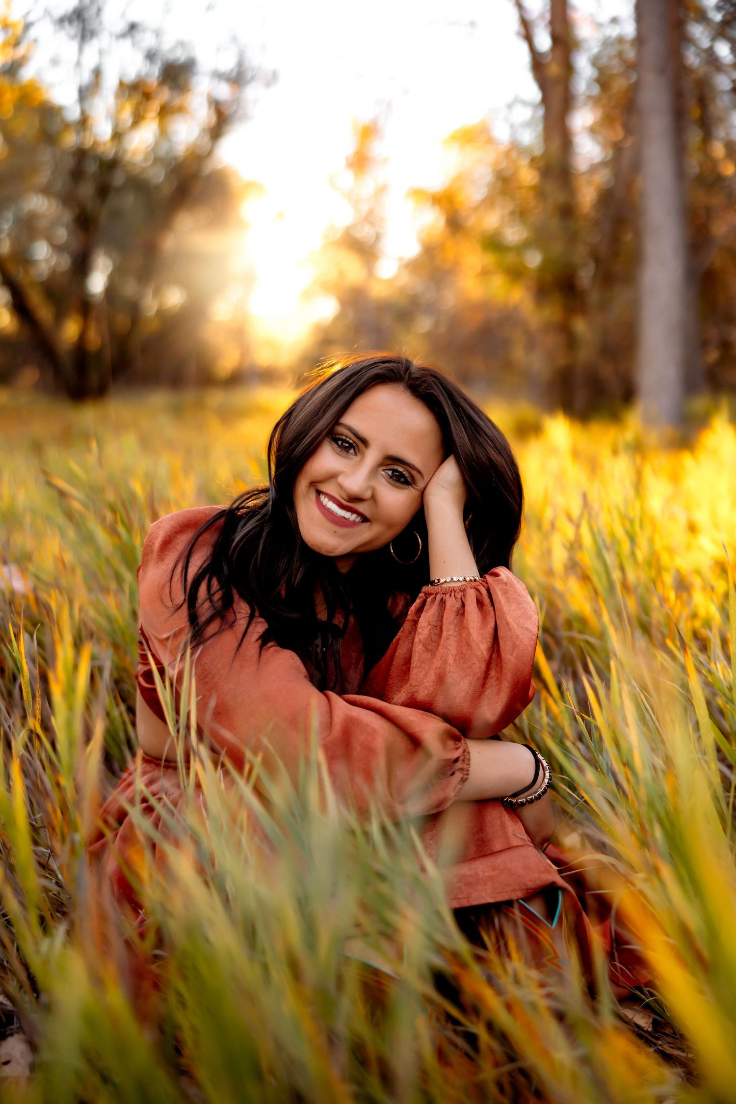 Natural outdoor portrait in rustic dress surrounded by glowing golden grass at sunset. Pueblo Photographer