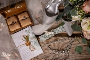 Wedding details flatlay with invitation, rings, and floral elements.