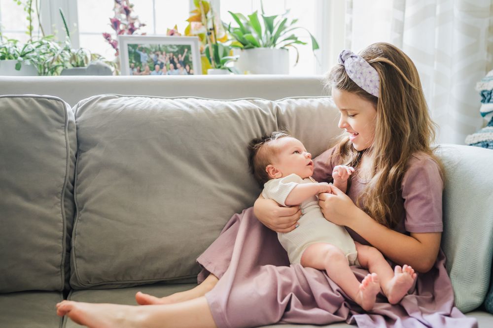 big-sister-cuddling-one-month-baby