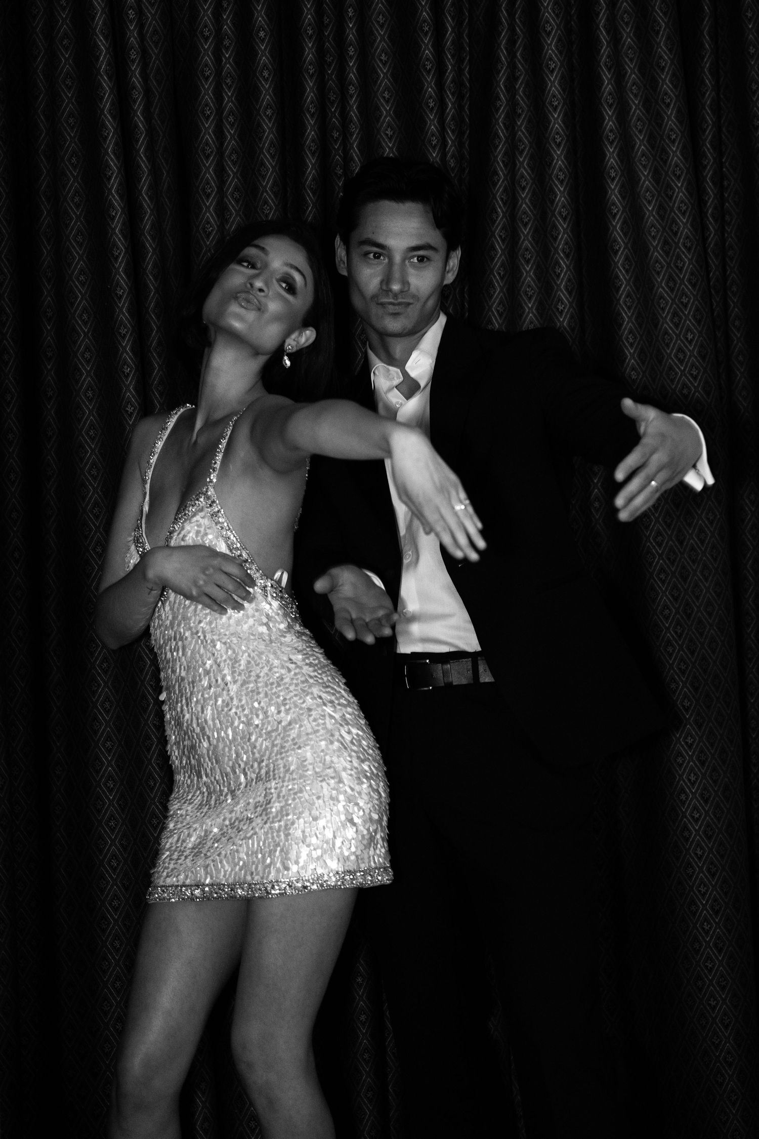 A glamorous couple dancing in evening attire, with the woman wearing a sparkly silver mini dress.