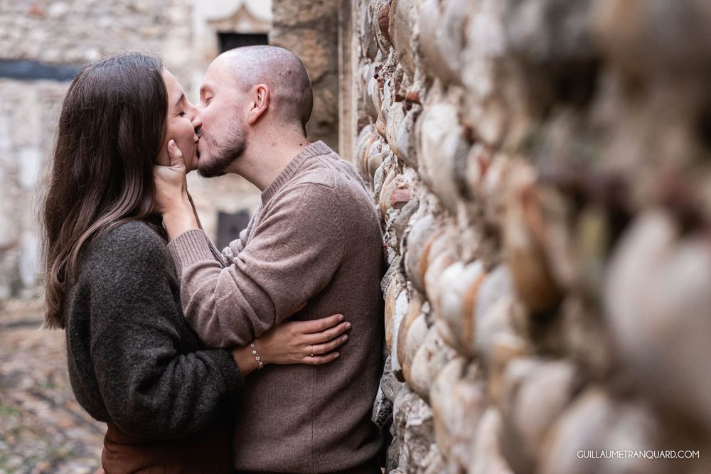 Intimate moment captured between couple against weathered brick wall backdrop.