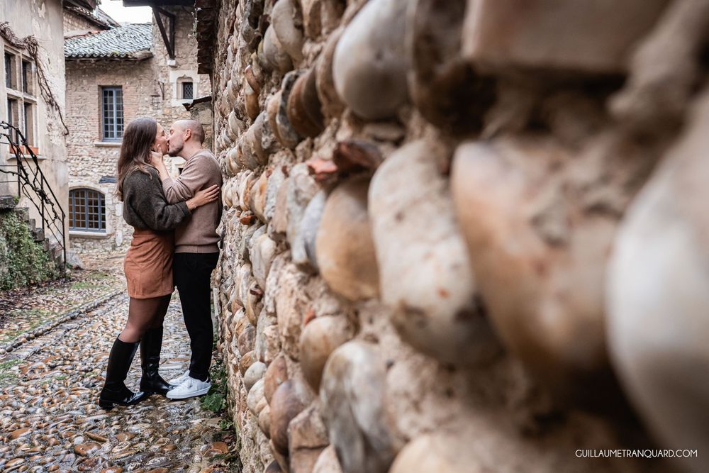 Artistic close-up shot of couple near textured stone wall with soft focus.