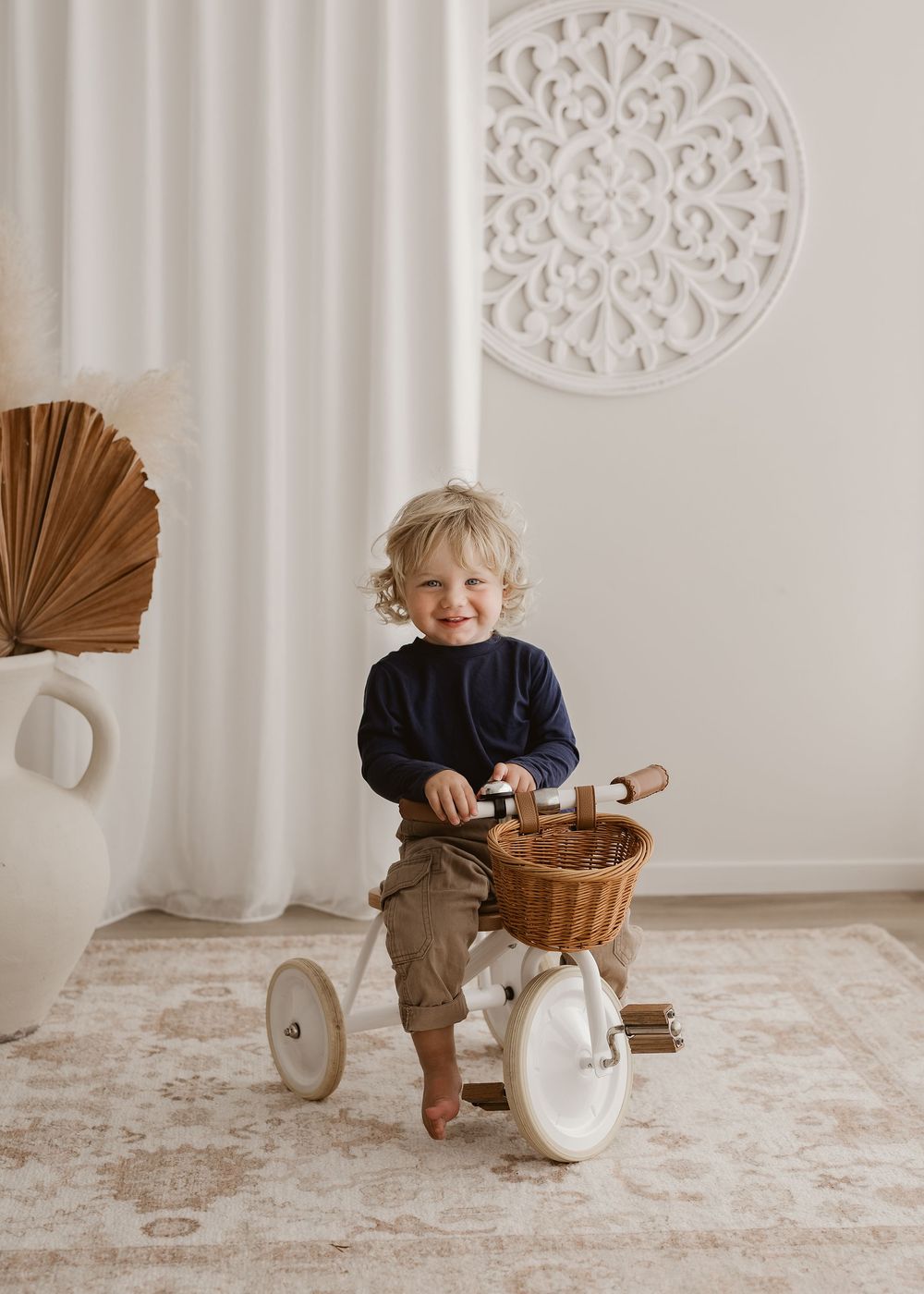 A sequence of five photos showing a child playing with a white ceramic teapot and woven basket on a light carpet.