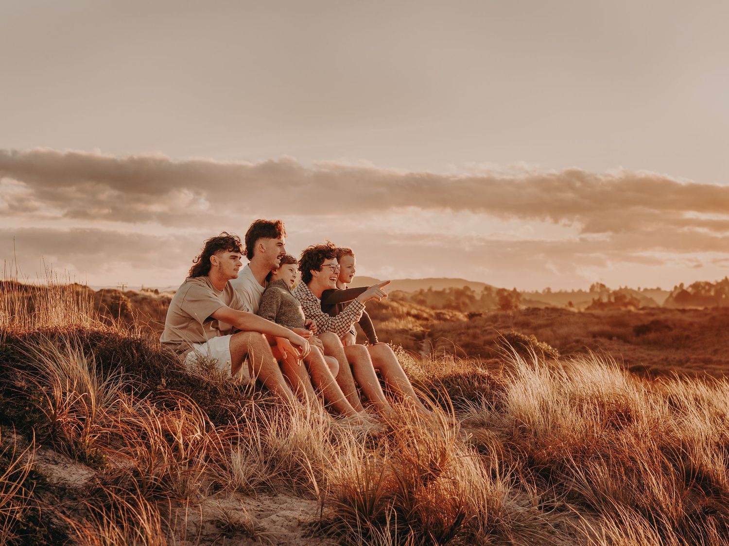 Family gathered among wildflowers in a serene autumn field during golden hour.
