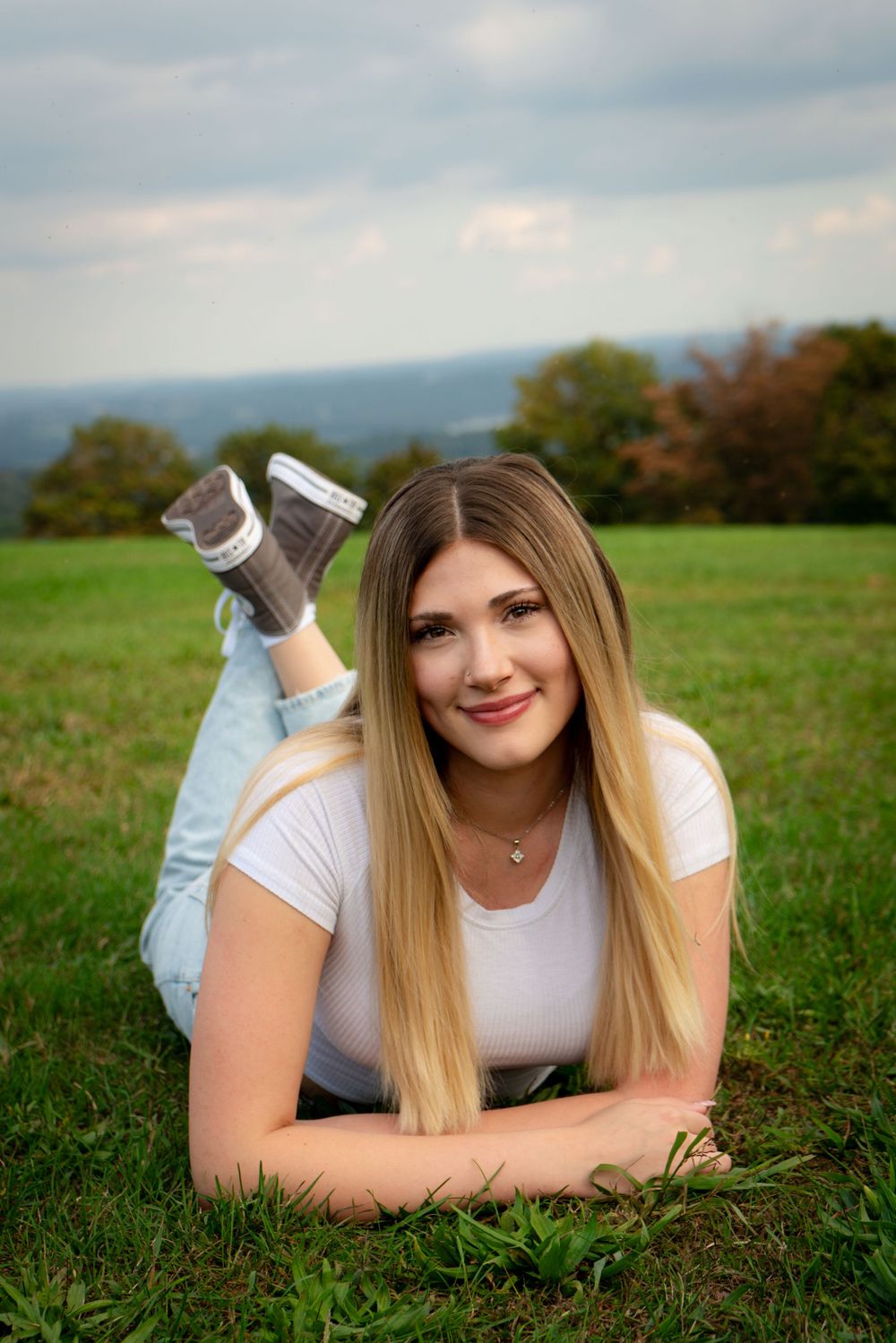 A relaxed outdoor portrait taken lying in green grass with mountains in the background.
