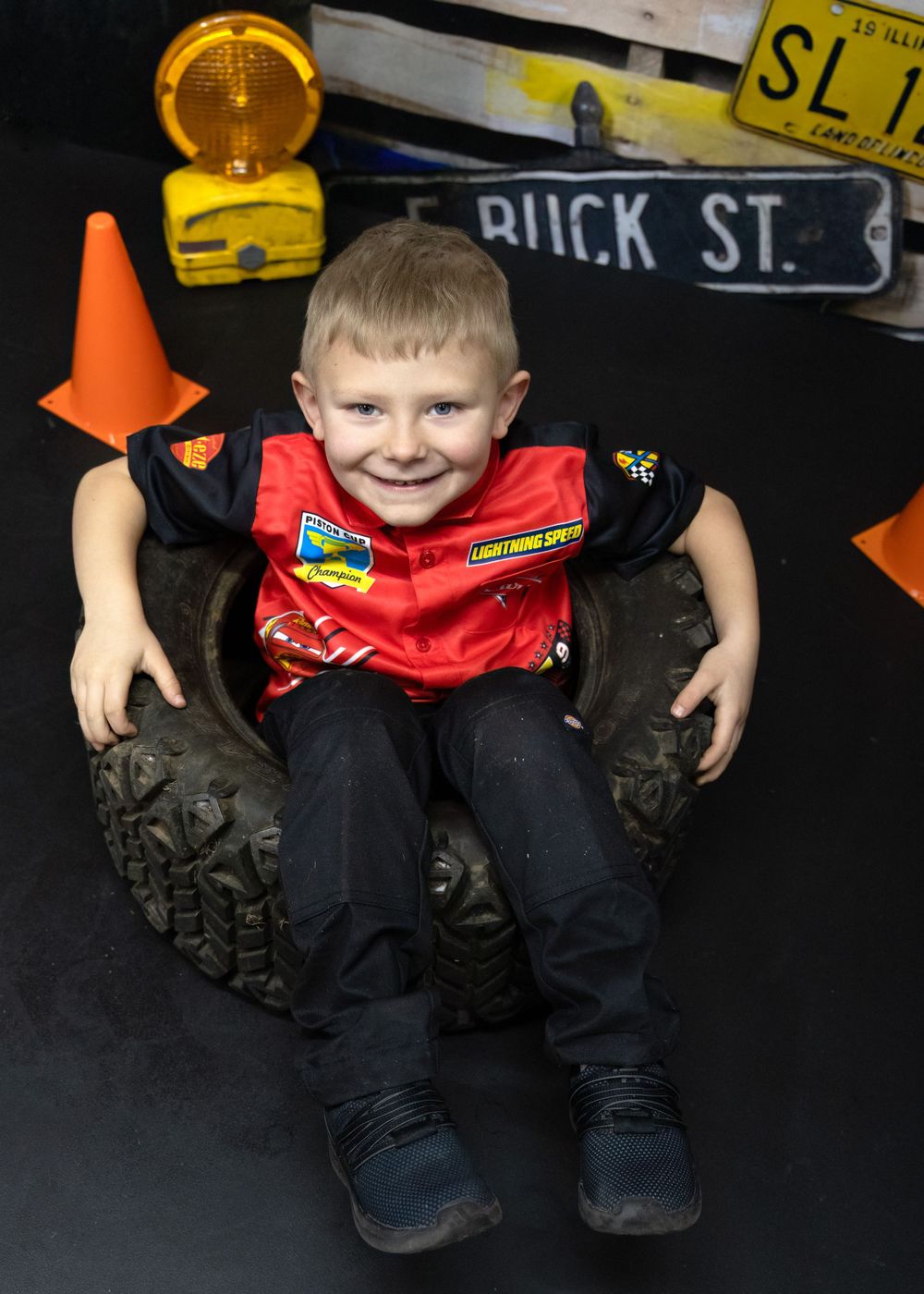 Racing-themed photo with construction cone and Buck St sign in dark background setting.