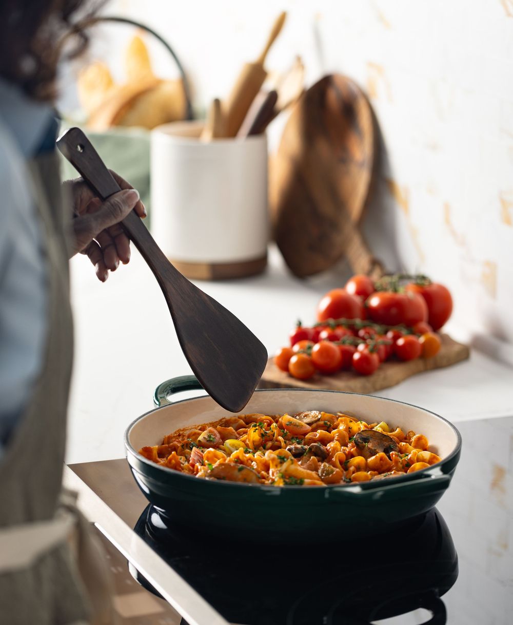Lifestyle photograph of a woman cooking pasta in studio kitchen in Los Angeles.