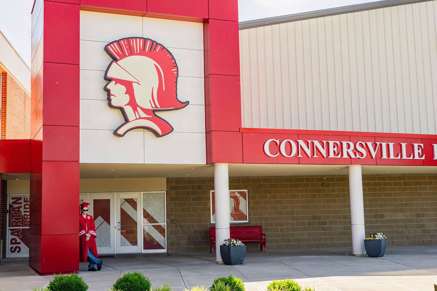 Red and white exterior of Connersville High School with Spartan mascot logo on the wall.