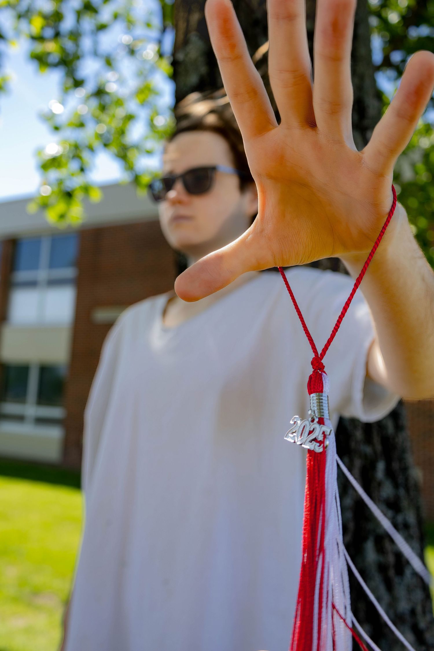 Hand holding graduation tassel with 2021 charm against blurred background.