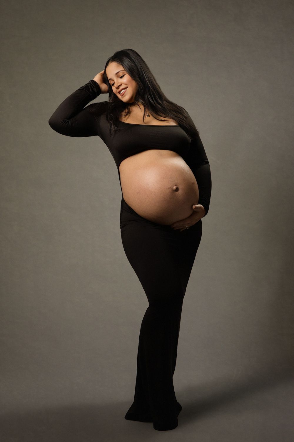 Artistic maternity photos showing a pregnant woman in black against gray backdrop in various elegant poses.