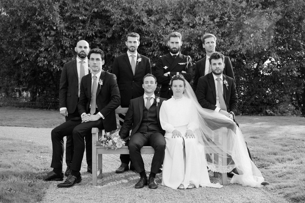Wedding party poses together outdoors on a grassy lawn in black and white formal attire.