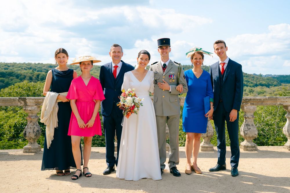 Wedding party stands together on a scenic overlook with mountains and blue sky in the background.