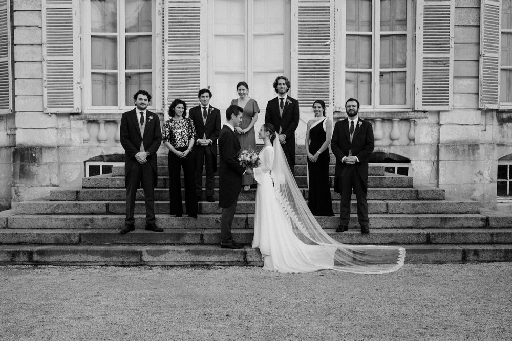 A black and white wedding party photo sequence showing a group posed on grand stone steps of a historic building.