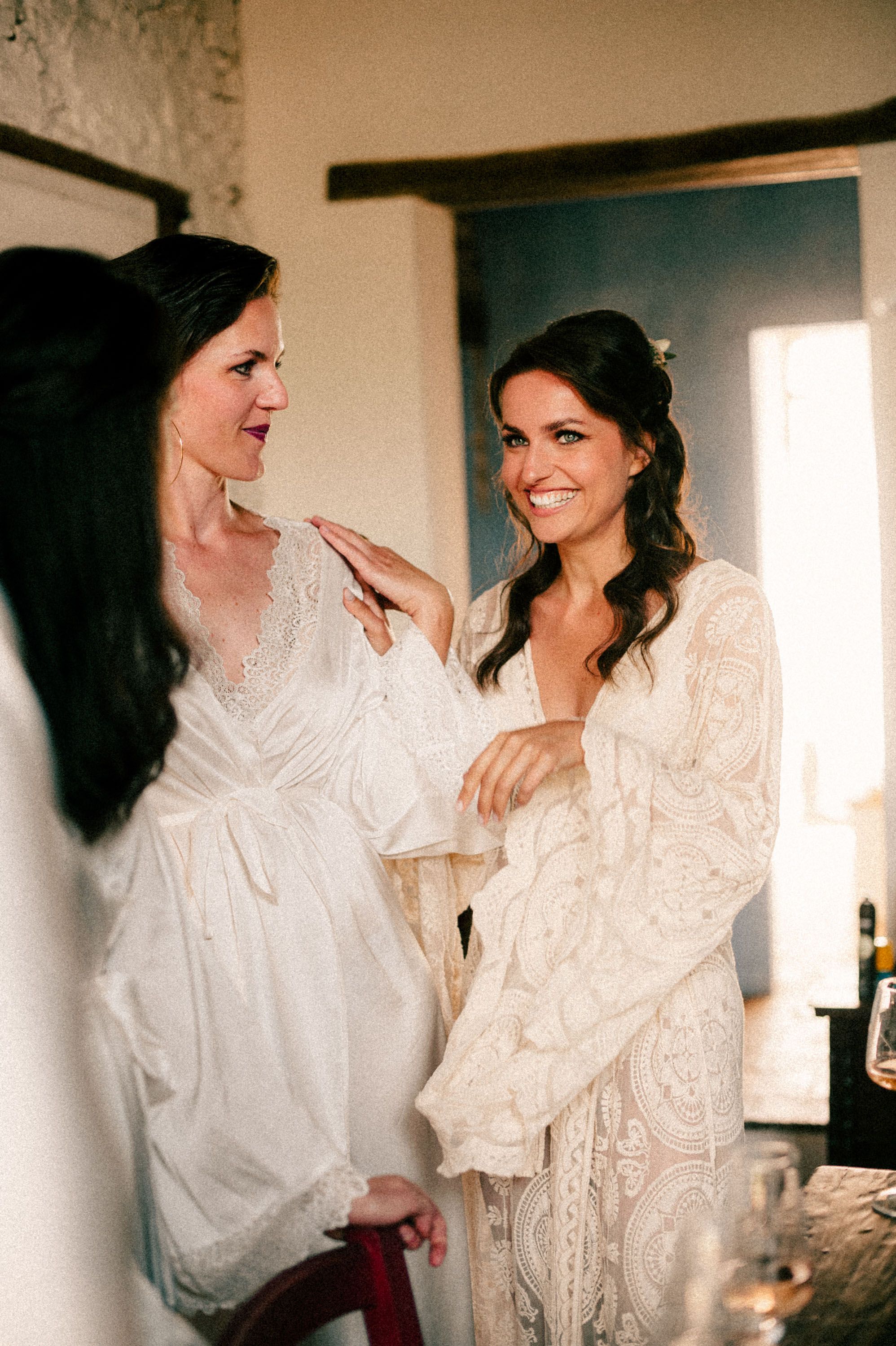 Wedding preparation scene with white robes and joyful moments in natural light.