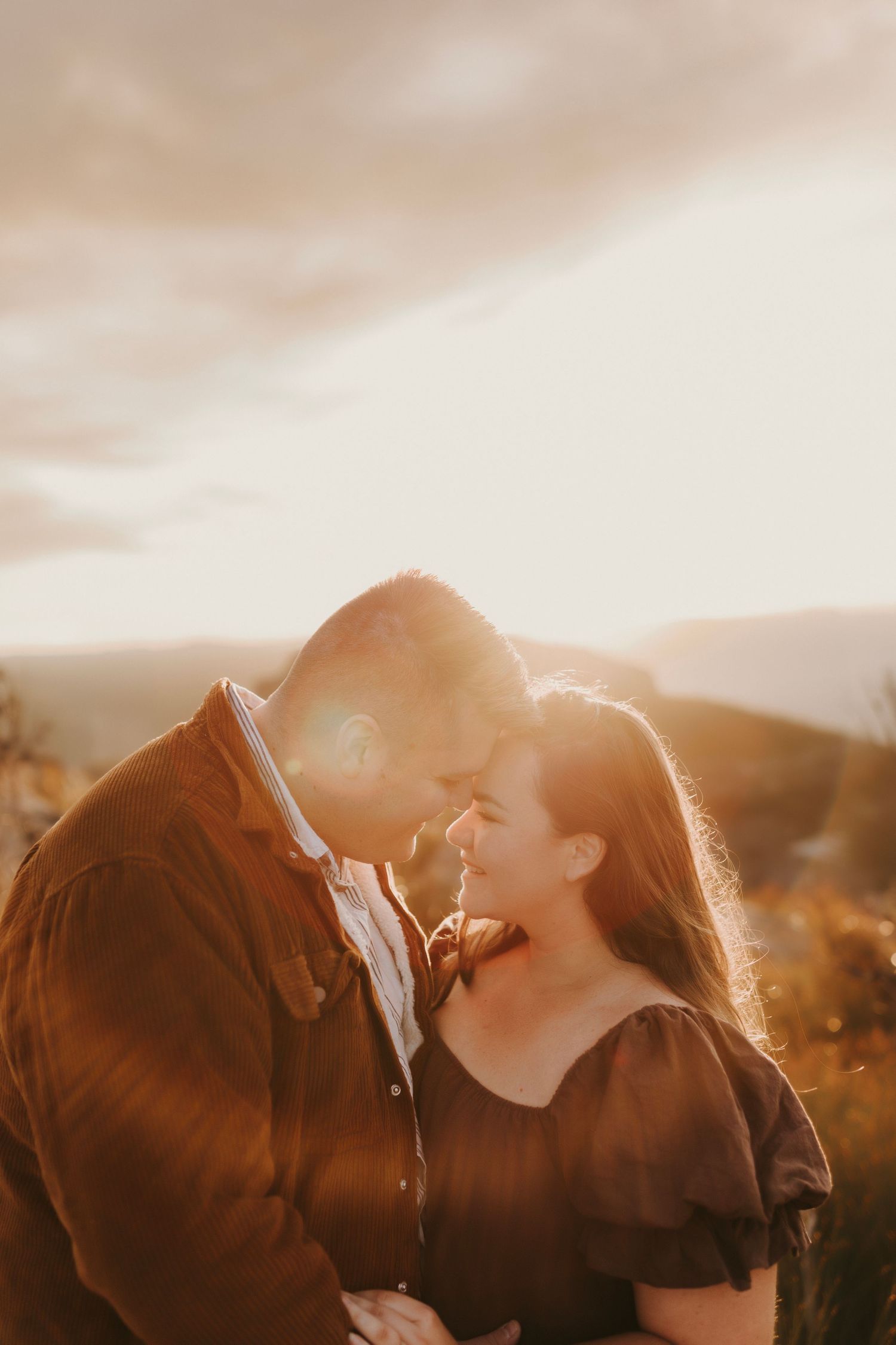 A romantic couple sharing an intimate moment in golden sunset light.