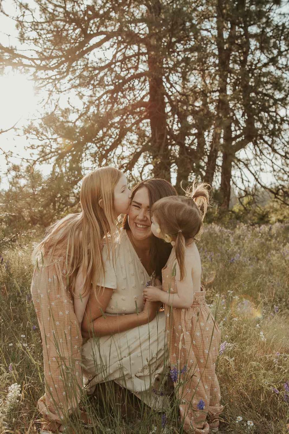 mother and daughter in earth tone dresses in a flower field snuggling at golden hour with a spokane family photographer