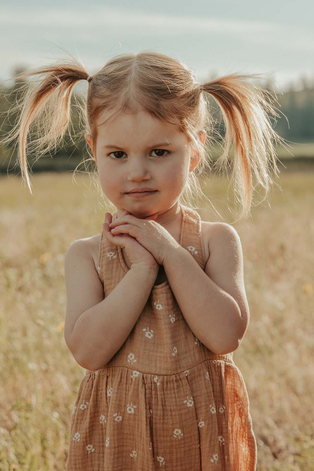 little girl in a brown romper in an open field at golden hour with a spokane family photographer