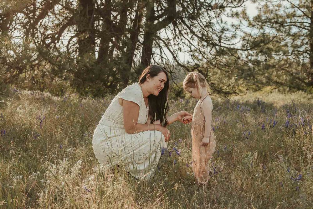 mother and daughter in earth tone dresses in a flower field at golden hour with a spokane family photographer