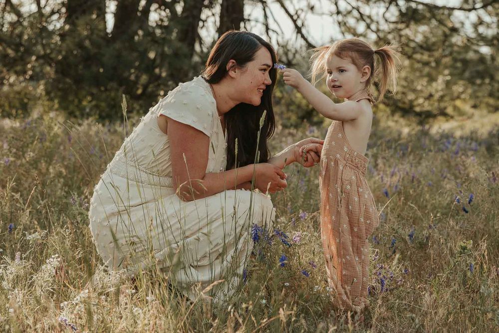 mother and daughter in earth tone dresses in a flower field at golden hour with a spokane family photographer