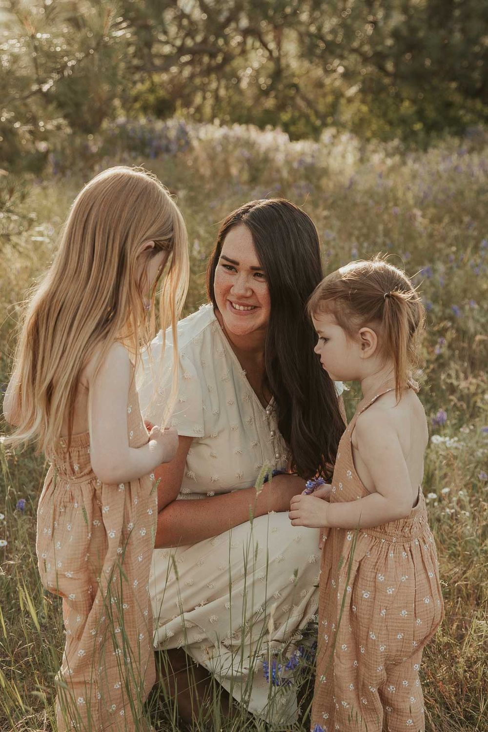 mother and daughter in earth tone dresses in a flower field laughing at golden hour with a spokane family photographer