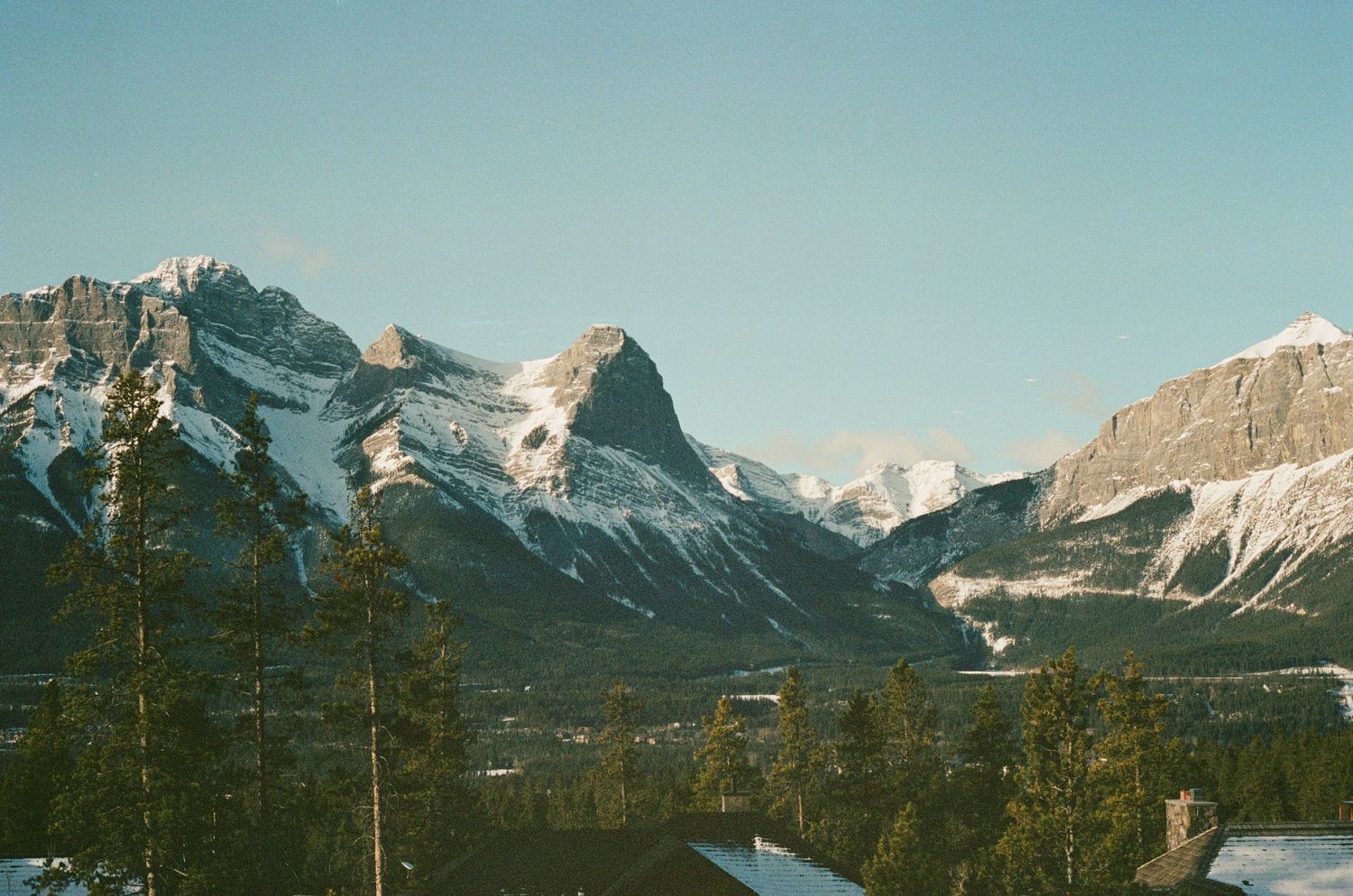 Majestic mountain range with snowy peaks reflected in valley below during winter.