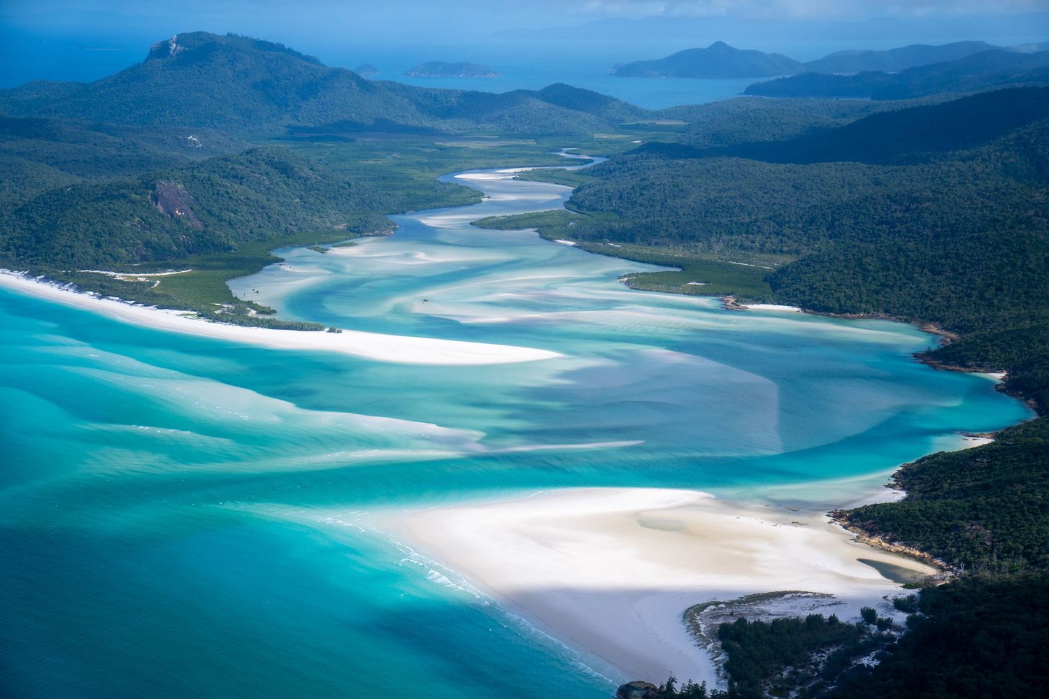Aerial view of turquoise waters and white sand beaches winding through coastal landscape.
