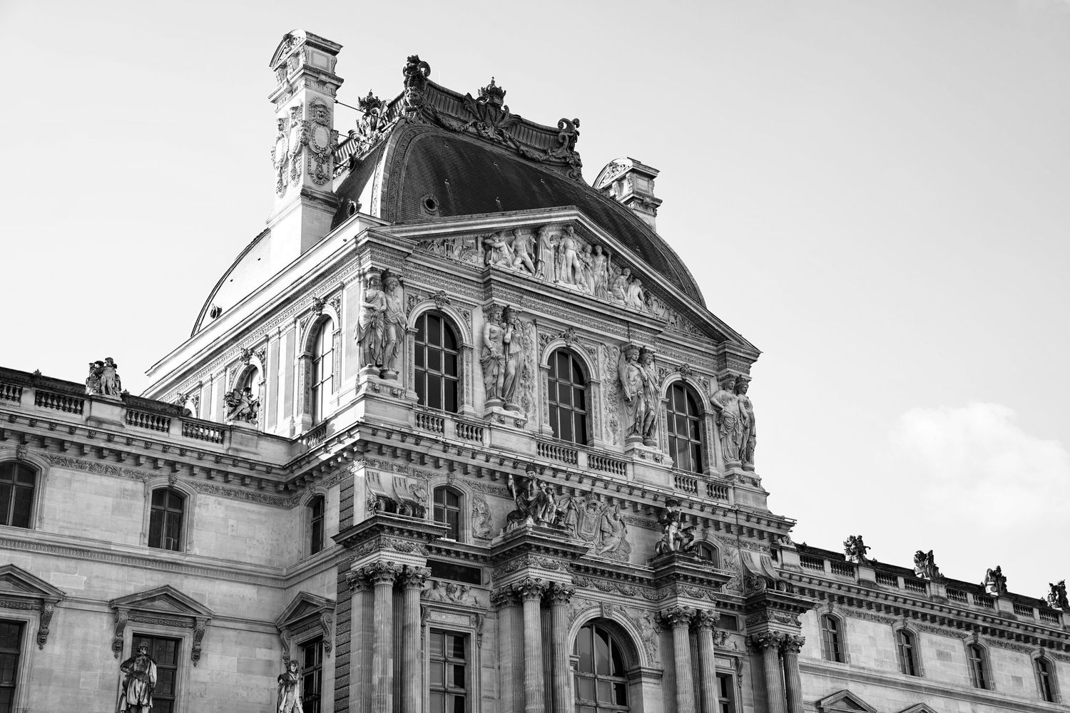 Black and white architectural detail of the ornate Louvre Museum facade in Paris.