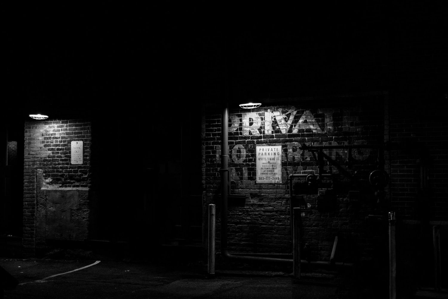 Dark nighttime photograph of brick wall with illuminated Private sign.