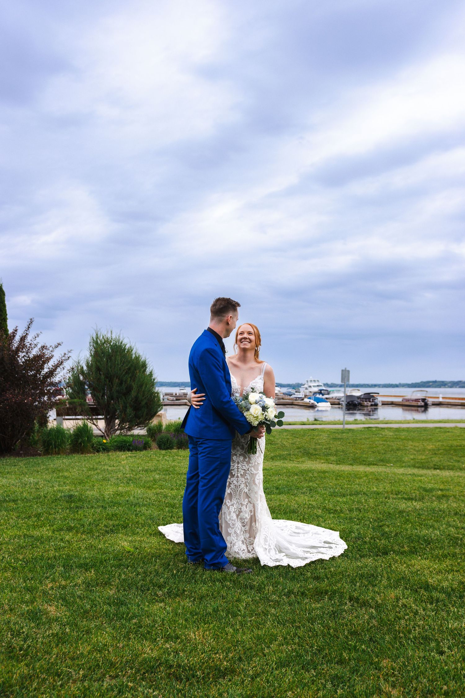 Waterfront wedding portrait on a cloudy day with boats and harbor in the background.