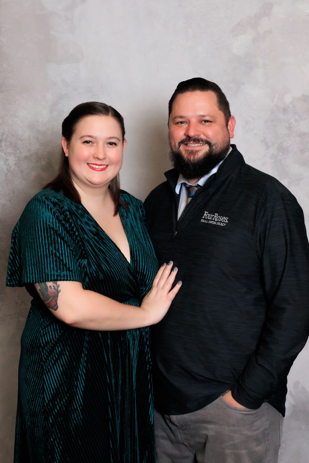 Couple poses in formal attire with woman in green velvet dress and man in quarter-zip pullover.